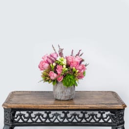 Pink roses arranged in a textured vase on a table