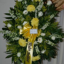 Large funeral wreath with yellow and white flowers on a stand