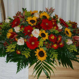 Large casket spray with red and yellow flowers and white roses