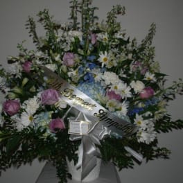 Large sympathy spray with pink roses, white daisies, and blue flowers