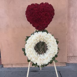 Heart-shaped red rose arrangement above a white rose wreath on an easel