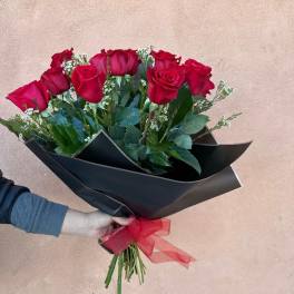 Bouquet of red roses wrapped in black paper with a red ribbon