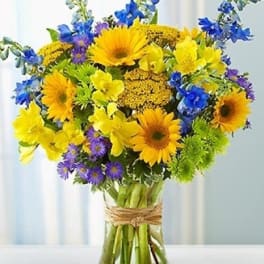 Bright mixed bouquet of yellow and blue flowers in a glass vase