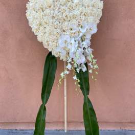 Heart-shaped white rose standing spray with orchids and long green leaves