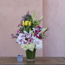 Tall bouquet of lilies, tulips, orchids, and hydrangeas in a green vase