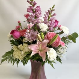 Pink and white mixed flower arrangement in a mauve vase