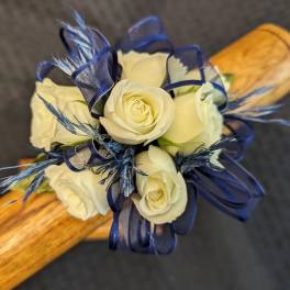Small cluster of ivory roses with navy ribbon and blue accents on a wooden handle