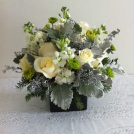 White roses and green-white flowers in a black square vase