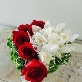 Red roses and white orchids arranged with pearl strands