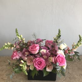 Pink roses and purple orchids in a black rectangular container
