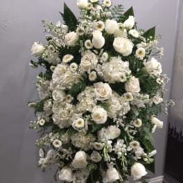 White floral standing spray with roses and daisies on an easel