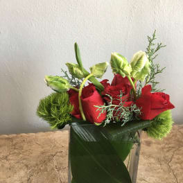 Red roses in a clear glass vase with green accents