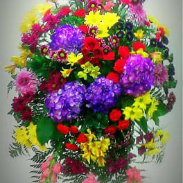 Large standing spray of mixed bright flowers on an easel