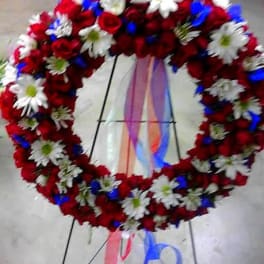 Heart-shaped floral wreath of red roses and white daisies on an easel