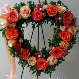 Heart-shaped rose wreath on an easel with peach and red blooms