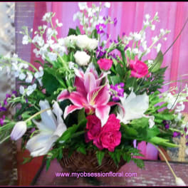 Basket arrangement with pink lilies, white blooms, and purple flowers