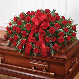 Red rose spray with a red ribbon on a wooden casket