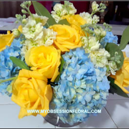 Bouquet of yellow roses and blue hydrangeas in a clear vase