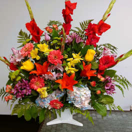 Colorful mixed flower arrangement in a white pedestal vase