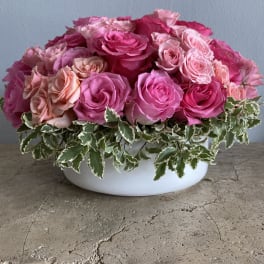 Pink and peach roses arranged in a white bowl vase