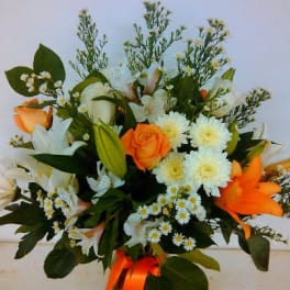 Bouquet of orange and white flowers in a glass vase with an orange ribbon