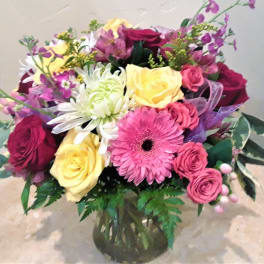 Mixed bouquet of roses, gerbera daisies, and chrysanthemums in a glass vase