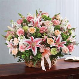 Basket arrangement of pink roses and lilies with a ribbon bow