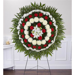 Circular funeral wreath with red and white flowers on a stand