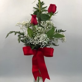 Tall bouquet of red roses with baby's breath in a glass vase and red ribbon