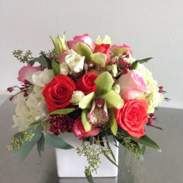 Mixed bouquet of red and pink roses with white blooms in a white vase