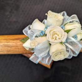 Small cluster of white roses with blue ribbon and blue gems arranged as a corsage