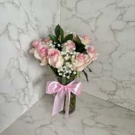 Pink roses in a glass vase with a pink ribbon