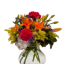 Colorful bouquet of lilies, carnations, and hydrangea in a clear glass vase