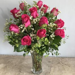 Pink roses arranged in a clear glass vase with small white filler flowers