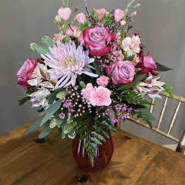Pink and lavender floral arrangement in a red vase