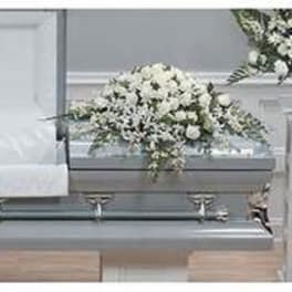 White floral casket spray on a gray casket