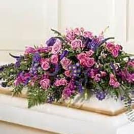 Large pink and purple floral casket spray on a white casket