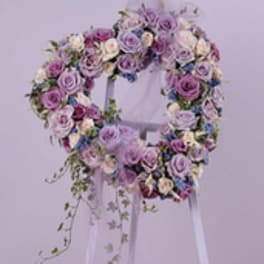 Lavender and pink rose wreath on a white stand with trailing greenery