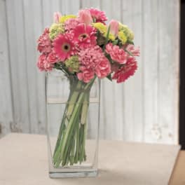 Pink mixed flowers arranged in a clear rectangular vase
