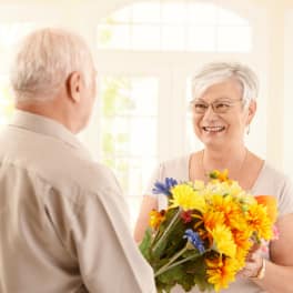 Smiling woman holding a colorful bouquet while facing an older man