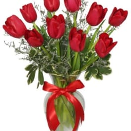 Red tulips in a glass vase with a red ribbon