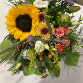 Mixed bouquet with a large sunflower, pink roses, and white blooms
