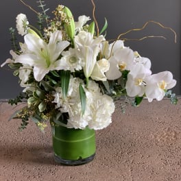 White lilies and orchids arranged in a green vase
