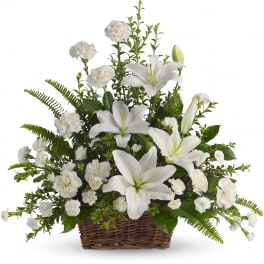 Basket arrangement of white lilies and white carnations in a brown woven basket