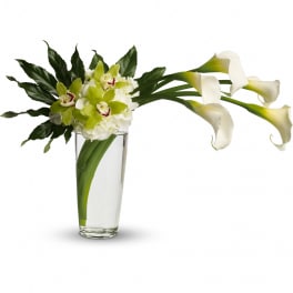 Tall glass vase with white calla lilies and green orchids in a modern asymmetrical design