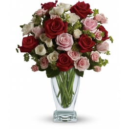 Tall clear glass vase filled with red, pink, and white roses.