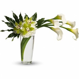White calla lilies and green orchids in a clear glass vase