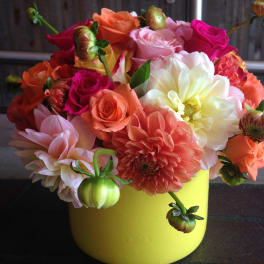 Colorful bouquet of roses and dahlias in a yellow container