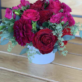 Bouquet of red and pink roses with a burgundy dahlia in a white vase