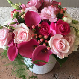 Pink roses and calla lilies arranged in a white vase